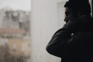 A depressed man looking out the window.