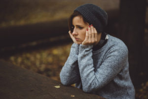 Portrait of sad, depressed woman sitting alone in the forest
