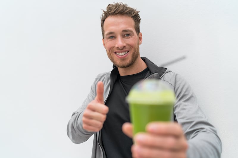 Happy healthy eating smoothie juice man thumbs up. Health food person drinking weight loss sport gre