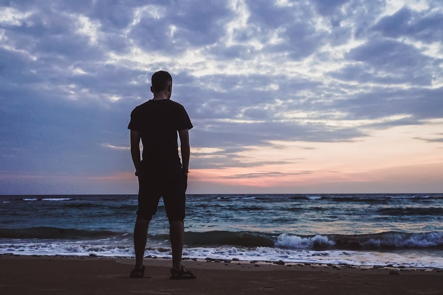 Man standing by the ocean thinking about faith-based heroin treatment.