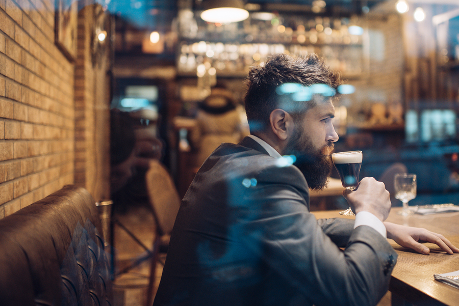 A businessman sitting in a bar drinking a glass of beer after work.