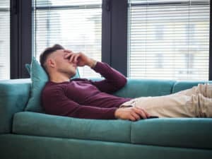 A man lying on the couch and contending with early signs of liver damage from drinking.
