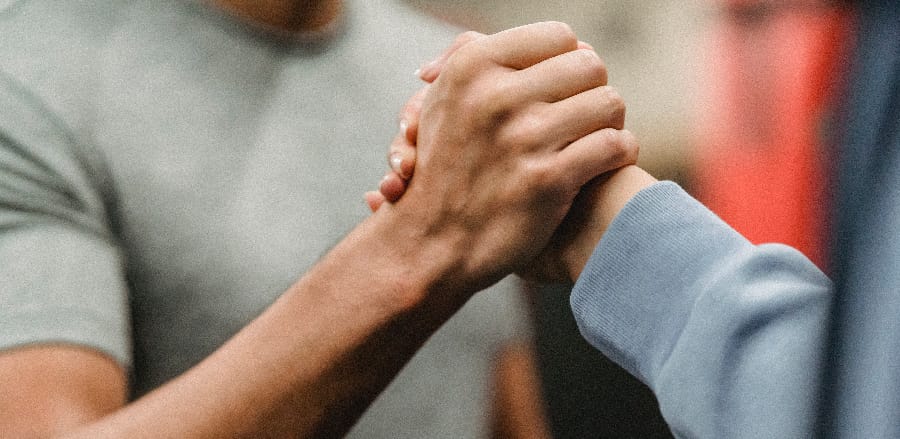 A close-up of two hands coming together in a firm handshake, representing the commitment and partnership between an individual and their support system in the journey to understanding alcohol's effects and seeking long-term sobriety.