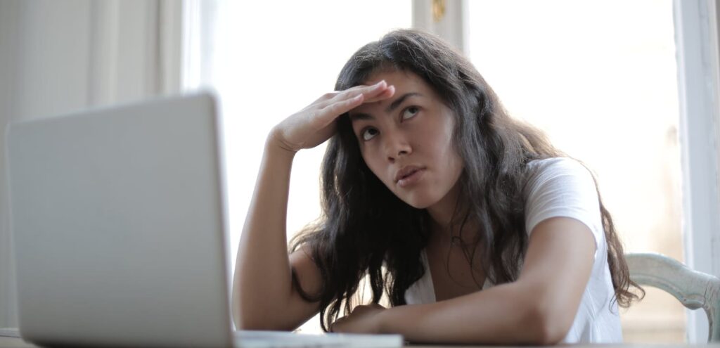 2. Woman looking confused at a computer screen, representing the challenges of understanding options for paying for addiction treatment.