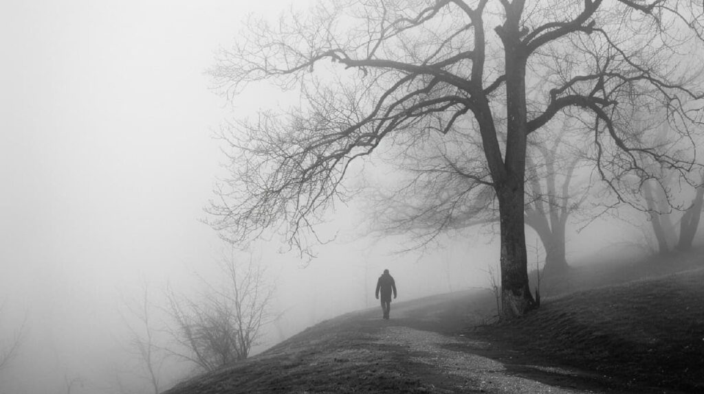 1. A lone man walks on a dimly lit path through thick fog, symbolizing the challenging journey of overcoming Xanax bar addiction
