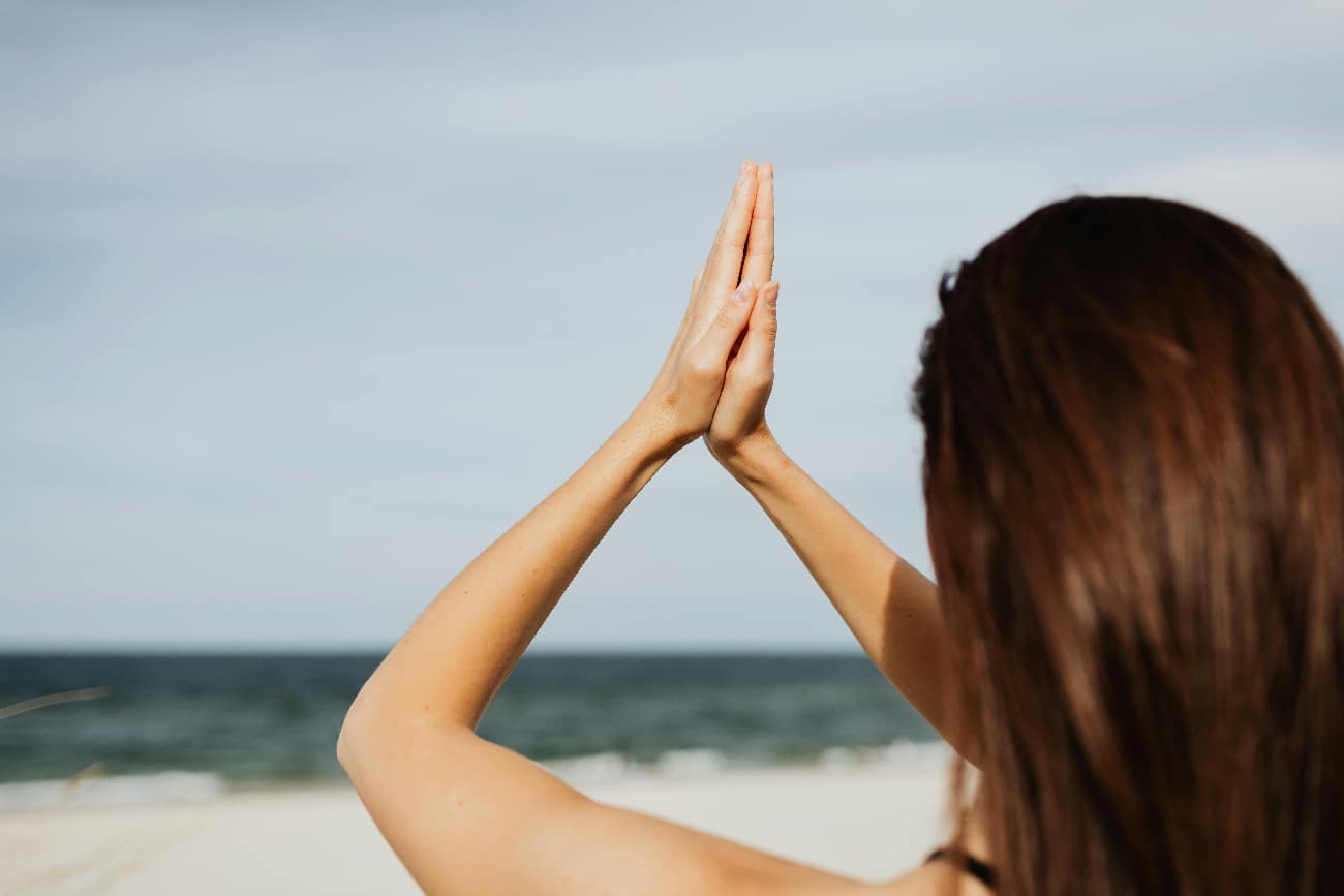 Woman prays at the beach to show the healing of prayer and how that can affect recovery and spirituality