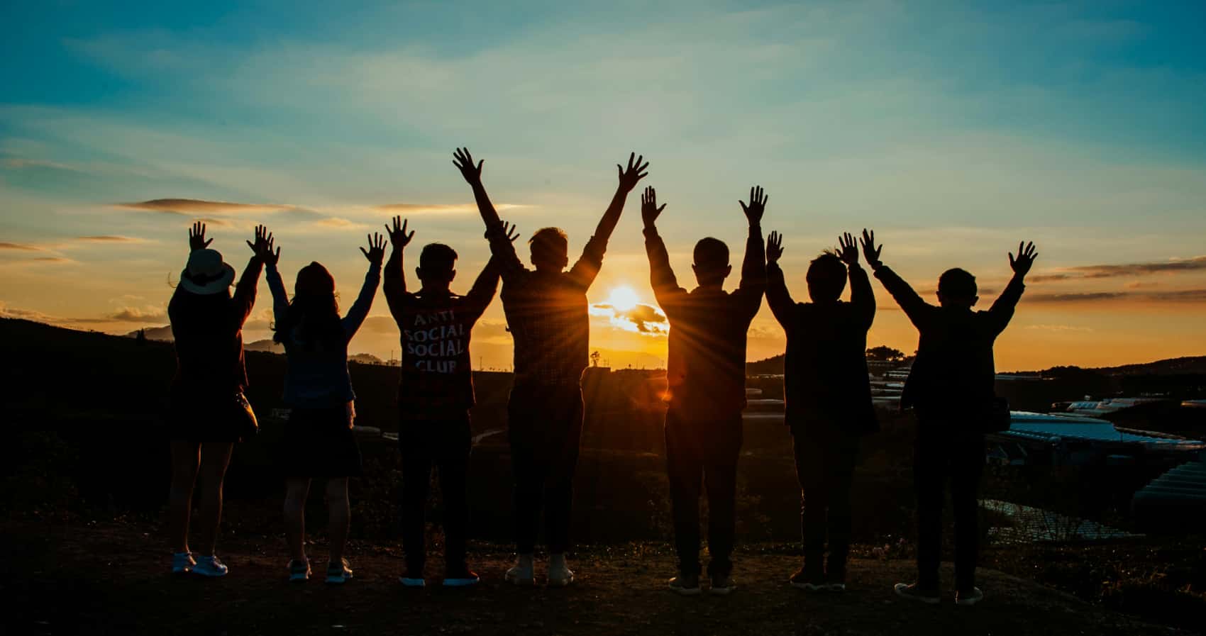 Friends at the beach with arms raised celebrating recovery to show after care in a rehab near Dana Point, CA