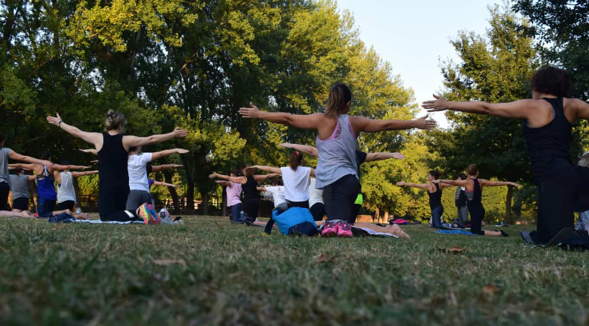 Women doing yoga on a grassy field to answer the question, "What is reahb?" showing it is holistic.