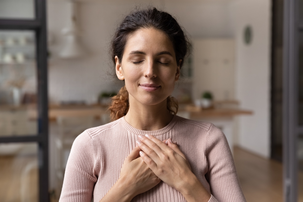 Woman with her hands on her chest while in Christian recovery treatment