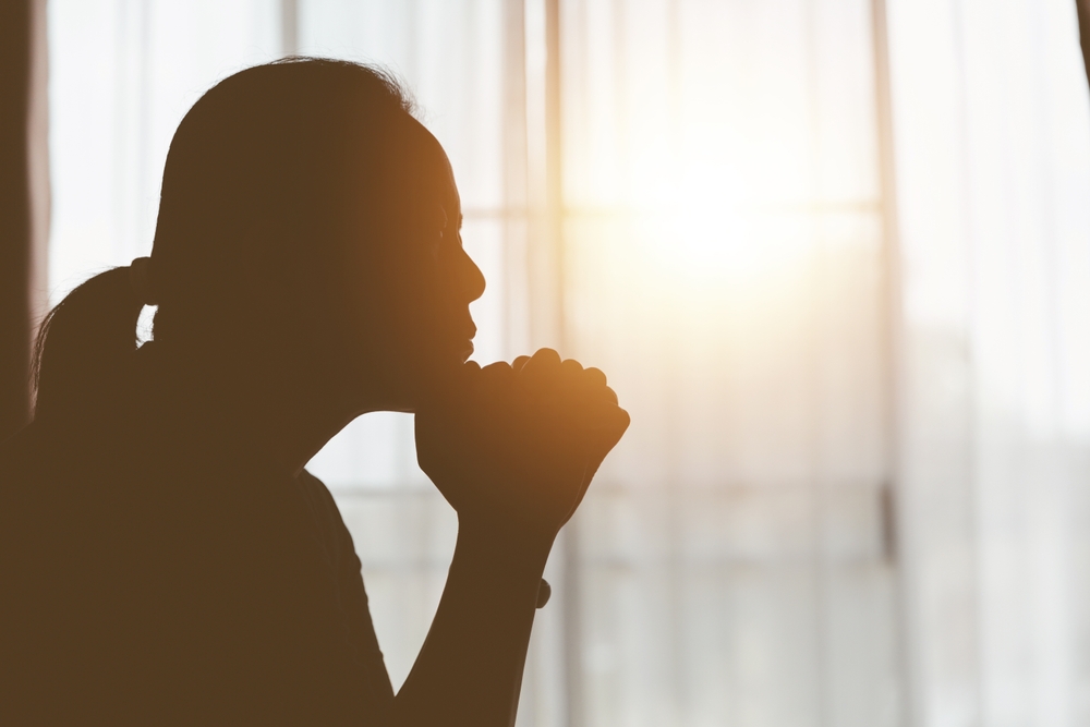 Silhouette of a female near a window during sunrise