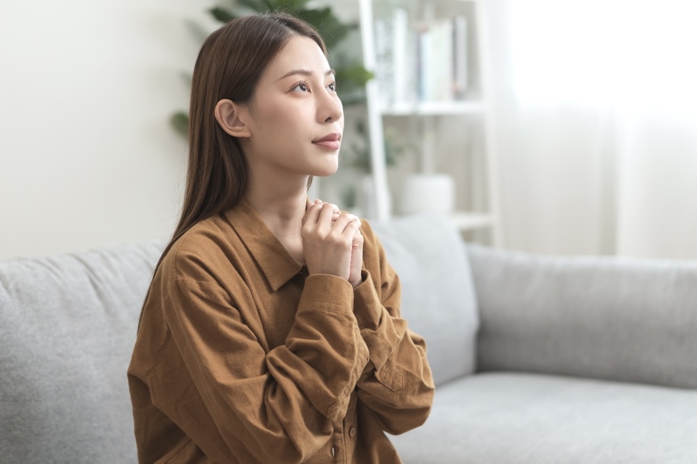 Woman in the living room saying prayers for family and friends in addiction 