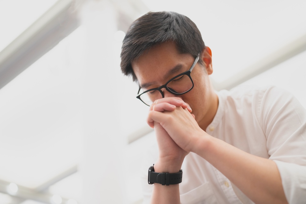 Man praying solemnly as he struggles with addiction issues 