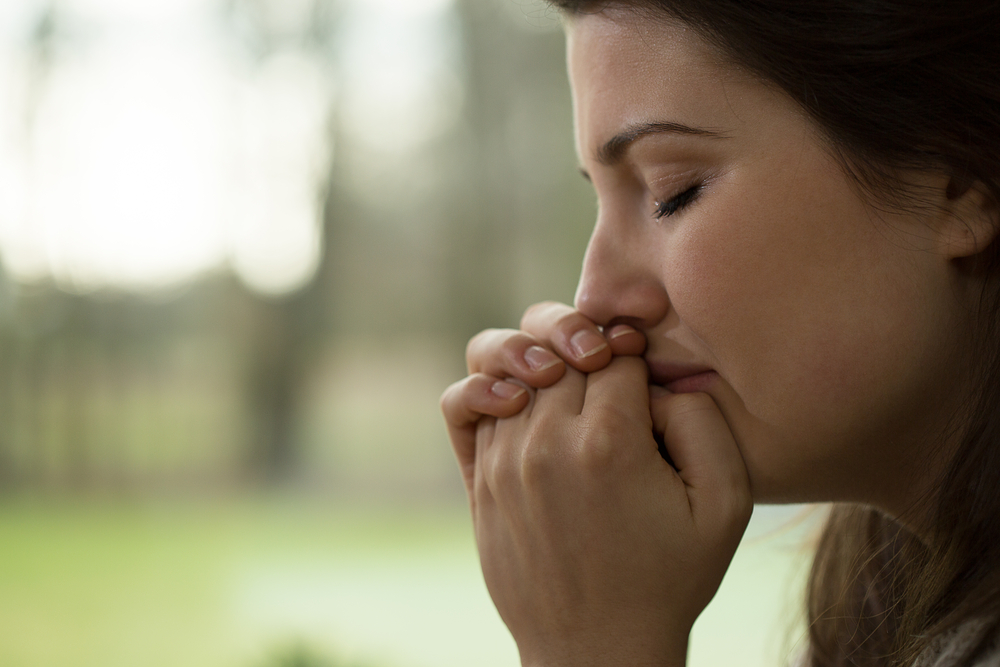 Female with closed eyes praying in tears 