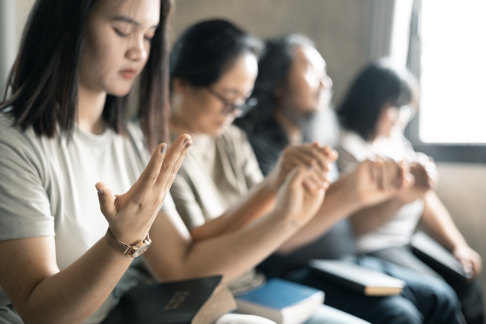 Group of females holding hands inside a Christian rehab 