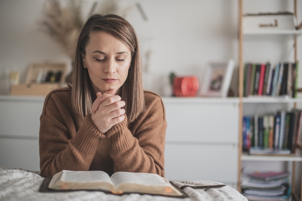 Woman praying solemnly in addiction recovery