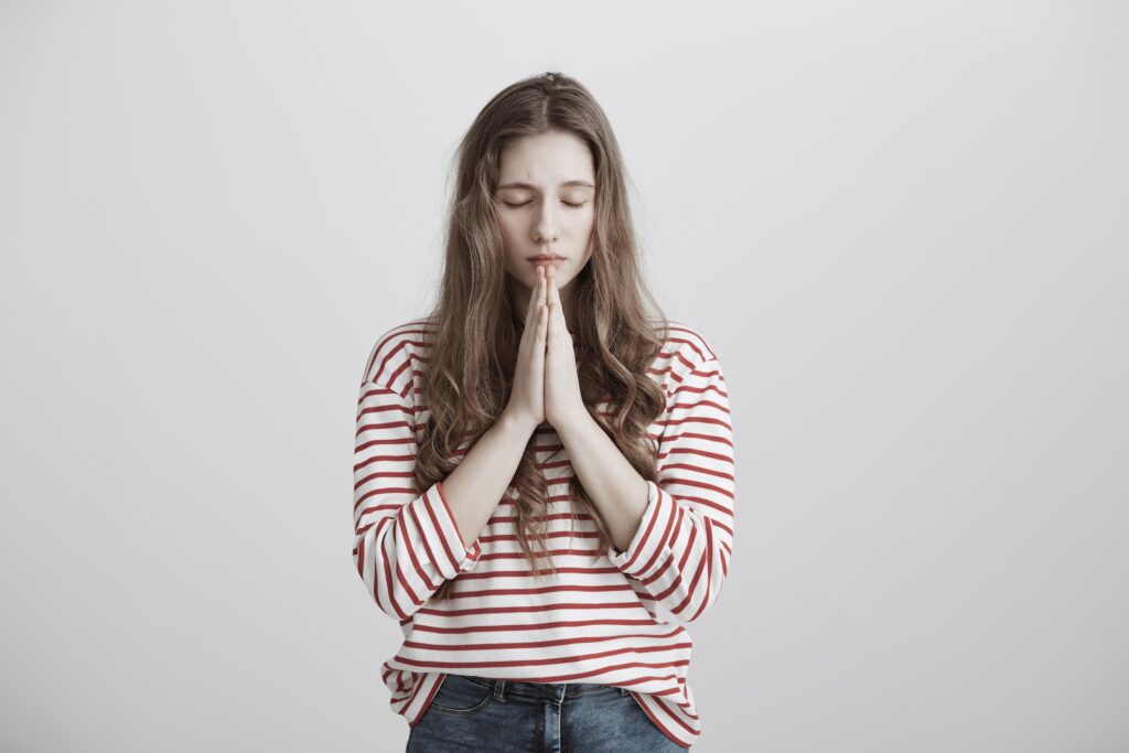 Woman in red striped shirt praying to relieve her anxiety and depression